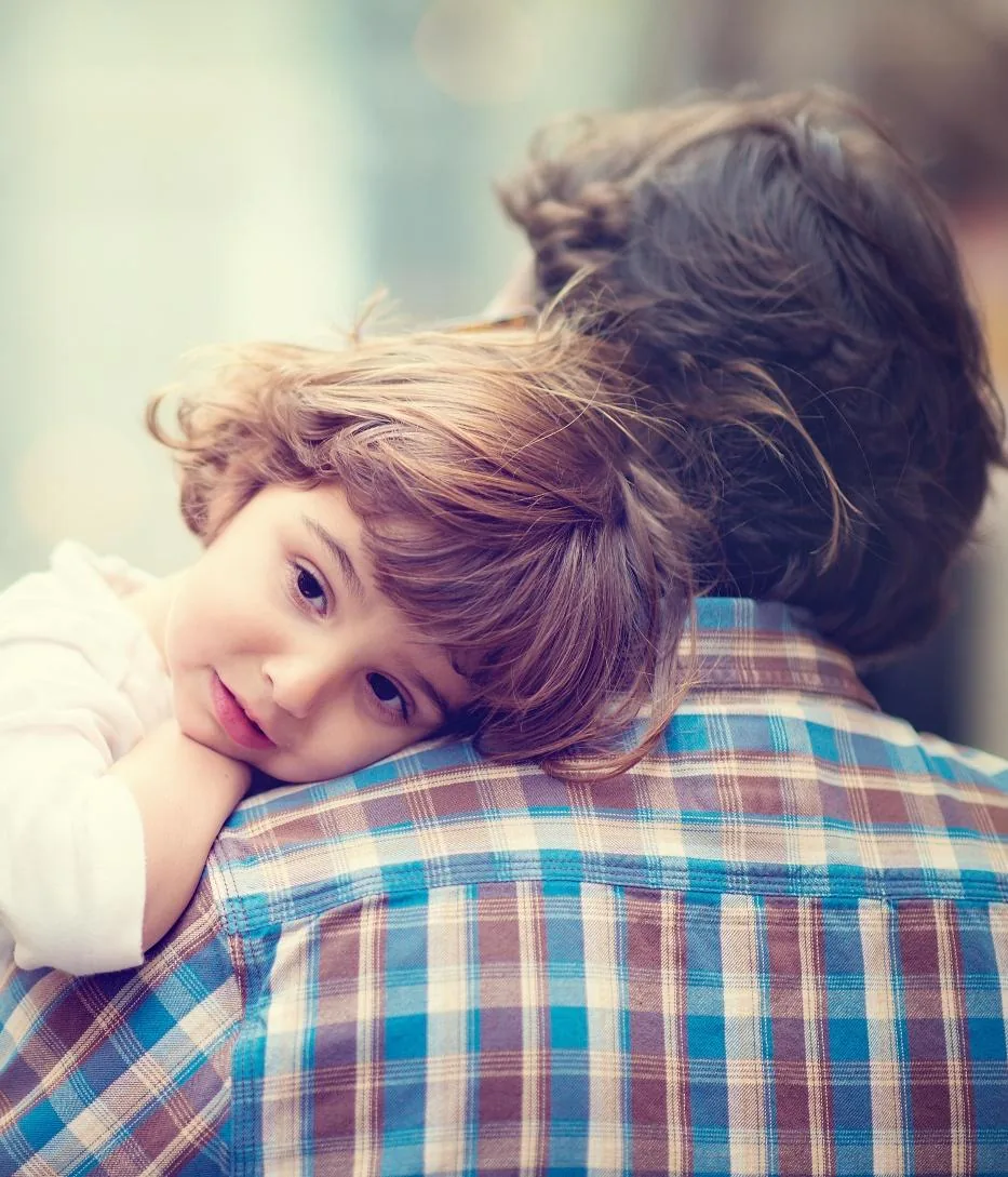 A young child resting on a parent's shoulder
