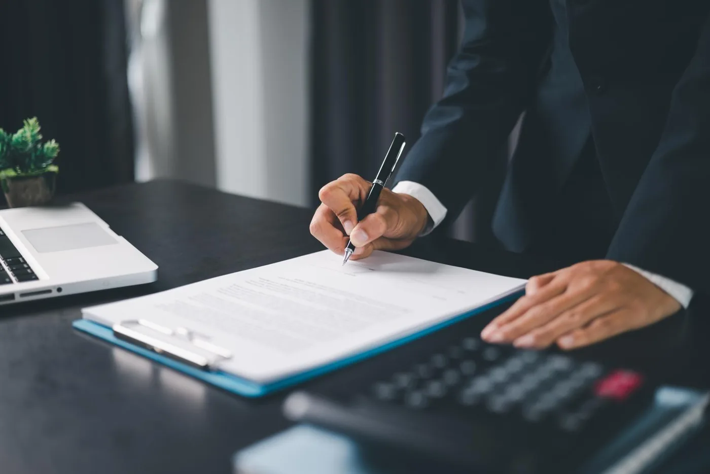 A person signing a document at a desk